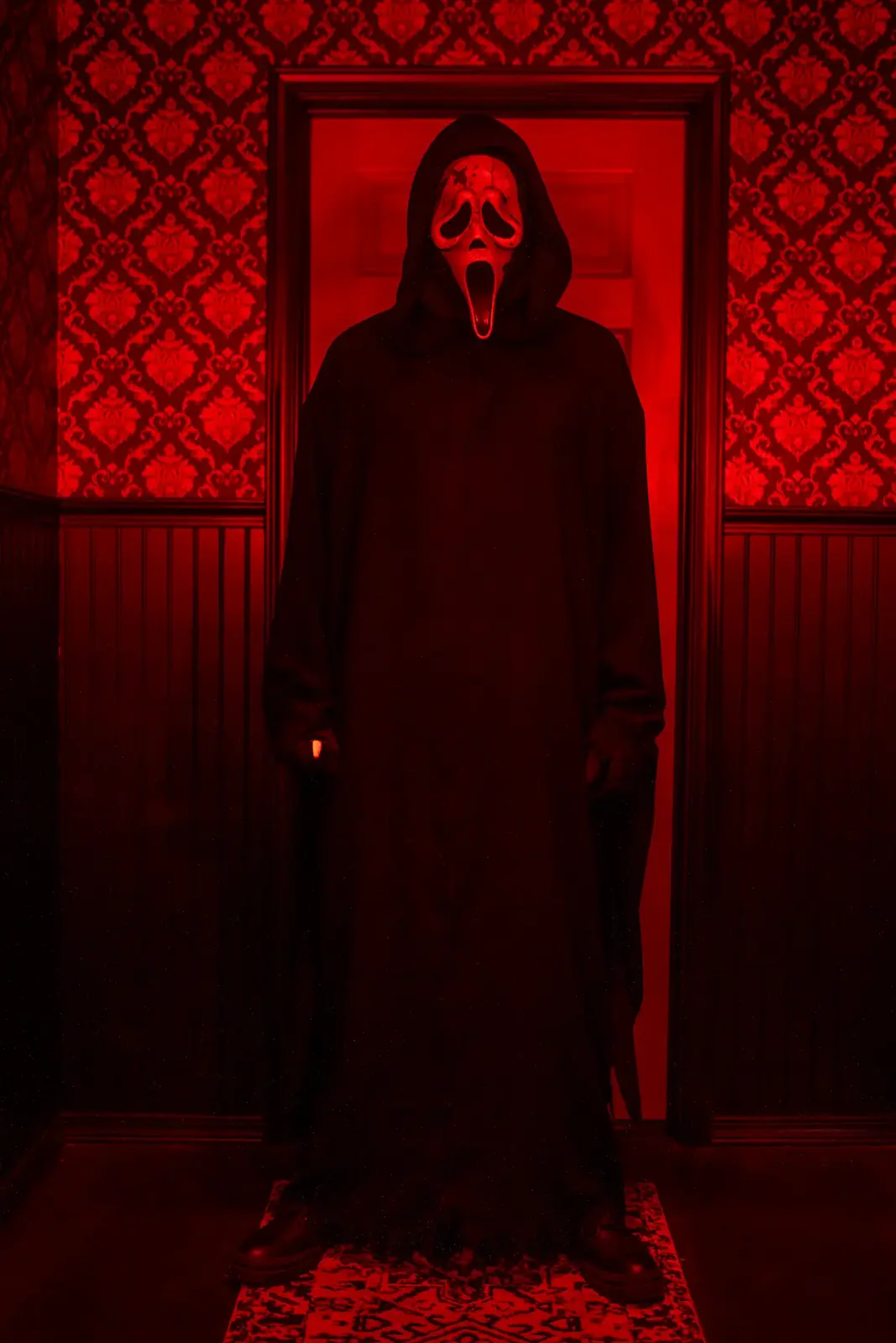 Ghostface standing in a red-lit doorway with damask wallpaper — horror portrait photography by Deadly Duvalls in Los Angeles